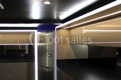 Cuisine moderne avec meubles laqués gris, plan de travail clair, micro-ondes et éclairage intégré.