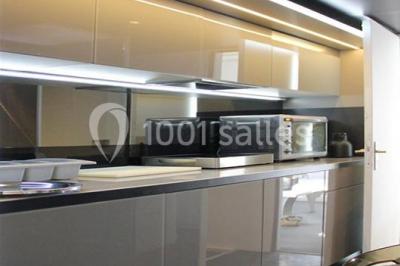 Cuisine moderne avec meubles laqués gris, plan de travail clair, micro-ondes et éclairage intégré.