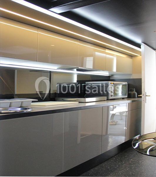 Cuisine moderne avec meubles laqués gris, plan de travail clair, micro-ondes et éclairage intégré.