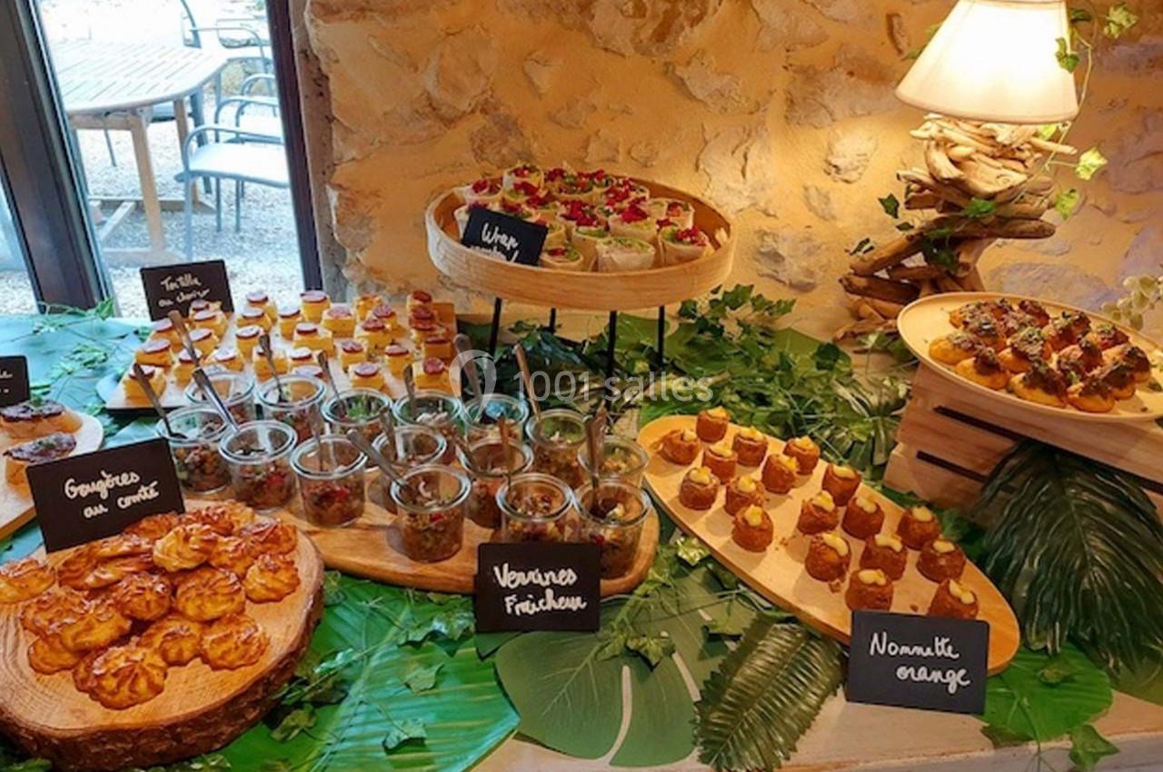 Buffet de petites bouchées sucrées et salées présentées sur des plateaux en bois, entourées de décorations végétales.