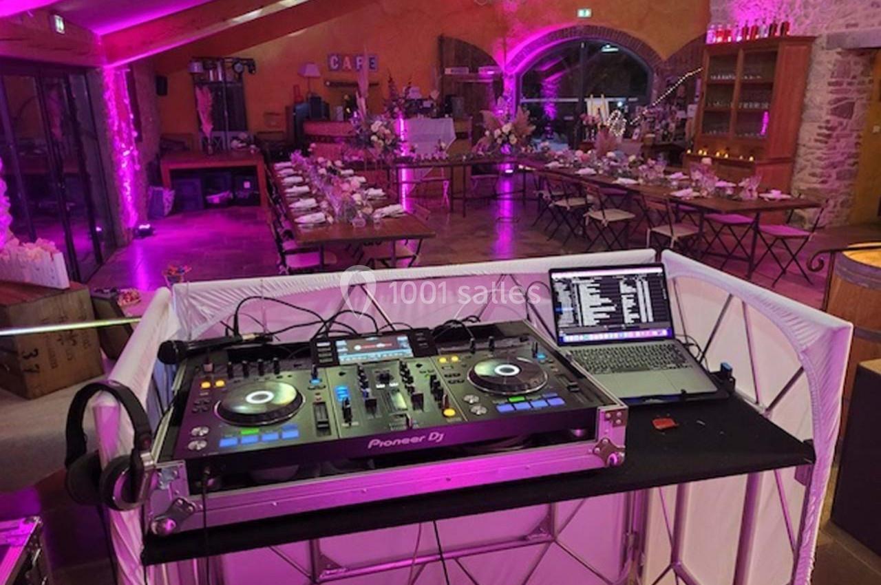 Console DJ avec platines et ordinateur portable dans une salle de réception décorée et éclairée en rose.