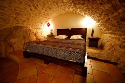 Lit avec serviettes roulées dans une chambre aux murs en pierre apparente et fenêtre laissant entrer la lumière naturelle.