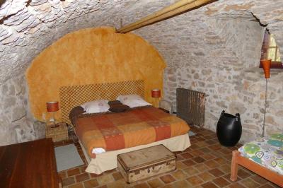 Lit avec serviettes roulées dans une chambre aux murs en pierre apparente et fenêtre laissant entrer la lumière naturelle.