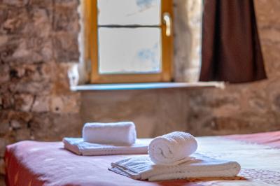 Lit avec serviettes roulées dans une chambre aux murs en pierre apparente et fenêtre laissant entrer la lumière naturelle.