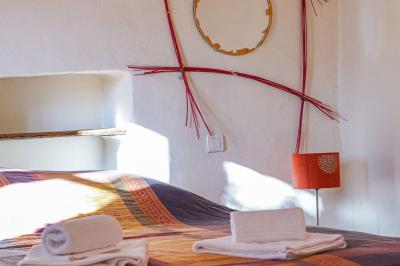 Lit avec serviettes roulées dans une chambre aux murs en pierre apparente et fenêtre laissant entrer la lumière naturelle.