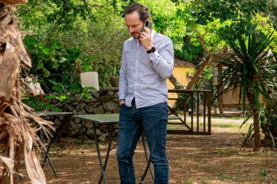 Lit avec serviettes roulées dans une chambre aux murs en pierre apparente et fenêtre laissant entrer la lumière naturelle.