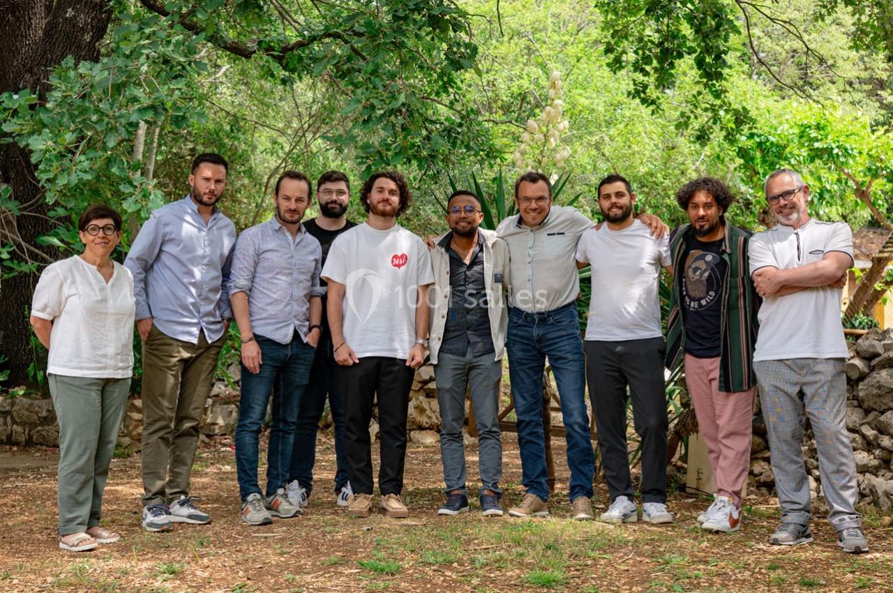 Un groupe de personnes posant debout à l'extérieur, entouré d'arbres et de verdure.