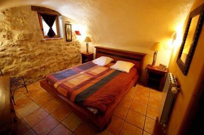 Lit double avec tête de lit en bois sculpté, draps blancs et serviettes pliées, dans une chambre aux murs en pierre.