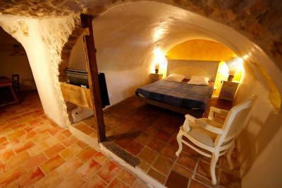 Lit double avec tête de lit en bois sculpté, draps blancs et serviettes pliées, dans une chambre aux murs en pierre.