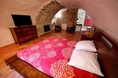 Lit double avec tête de lit en bois sculpté, draps blancs et serviettes pliées, dans une chambre aux murs en pierre.