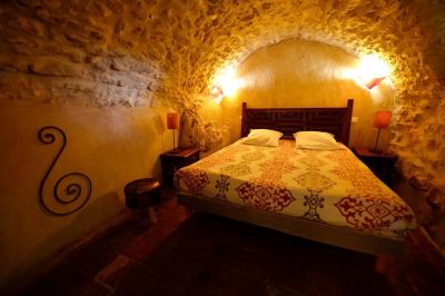 Lit double avec tête de lit en bois sculpté, draps blancs et serviettes pliées, dans une chambre aux murs en pierre.