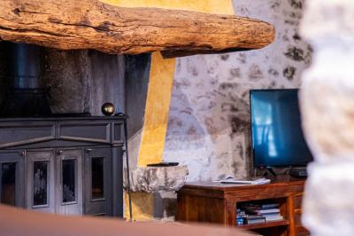 Lit double avec tête de lit en bois sculpté, draps blancs et serviettes pliées, dans une chambre aux murs en pierre.