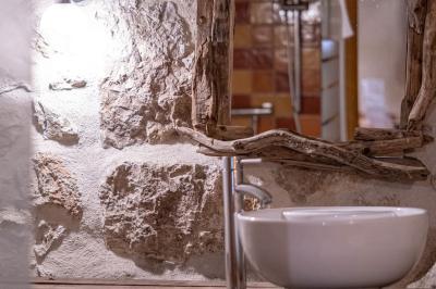 Lit double avec tête de lit en bois sculpté, draps blancs et serviettes pliées, dans une chambre aux murs en pierre.