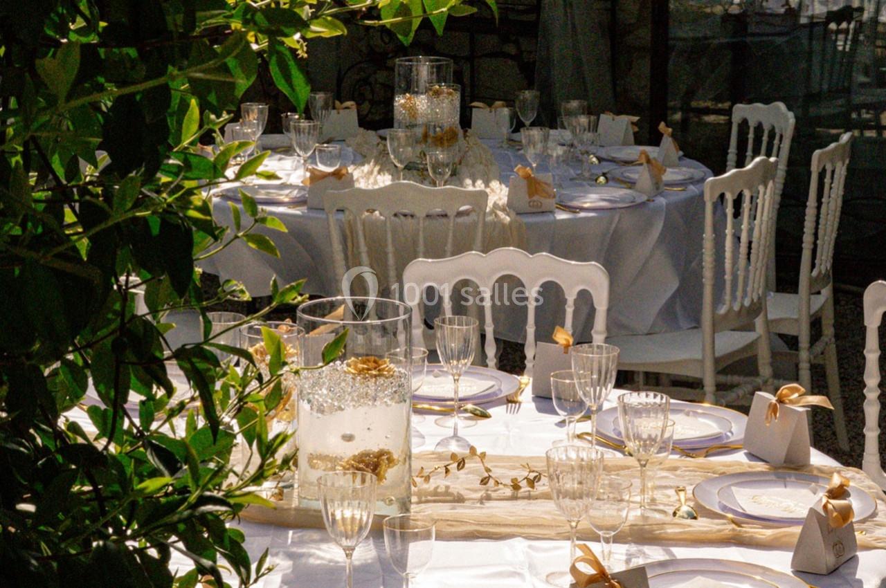 Tables élégamment dressées avec nappes blanches, chaises assorties et décorations raffinées dans un cadre ensoleillé.