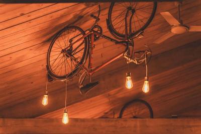 Façade d'une maison beige à volets verts, reflétée dans un bassin entouré de pierres et de végétation.