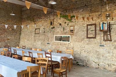 Façade d'une maison beige à volets verts, reflétée dans un bassin entouré de pierres et de végétation.