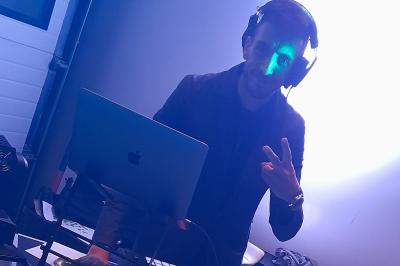 Un DJ mixant de la musique sur une table de mixage avec un ordinateur portable dans un environnement lumineux.