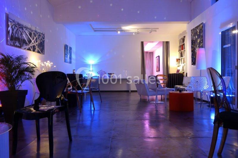 Salle moderne avec éclairage tamisé coloré, mobilier varié et décoration murale artistique.