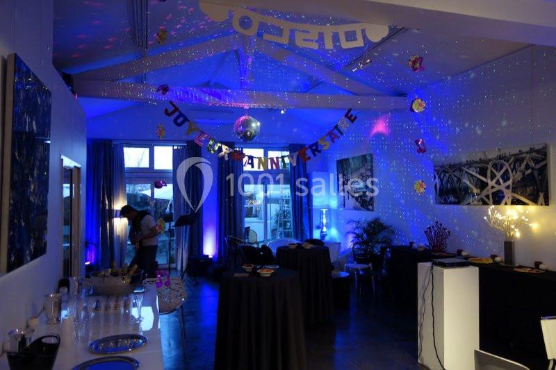 Salle décorée pour un anniversaire avec guirlandes, lumières colorées et tables dressées pour une réception.