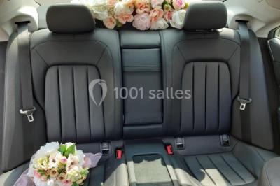 Banquette arrière d'une voiture avec des fleurs blanches et roses disposées sur la plage arrière et un bouquet sur le siège.