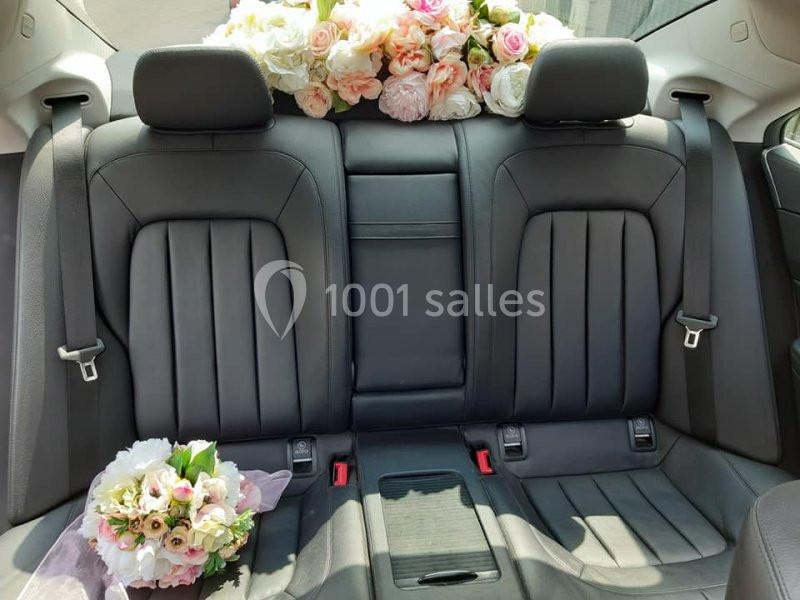 Banquette arrière d'une voiture avec des fleurs blanches et roses disposées sur la plage arrière et un bouquet sur le siège.