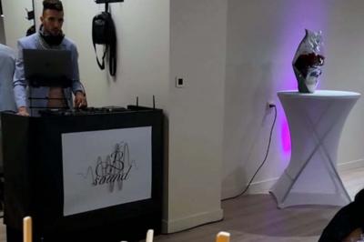 Un DJ mixant de la musique sur une table de mixage avec un ordinateur portable dans un environnement lumineux.