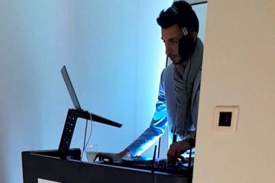 Un DJ mixant de la musique sur une table de mixage avec un ordinateur portable dans un environnement lumineux.