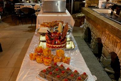 Table garnie de desserts variés, dont des gâteaux, des verrines de fruits et une pièce montée décorée.
