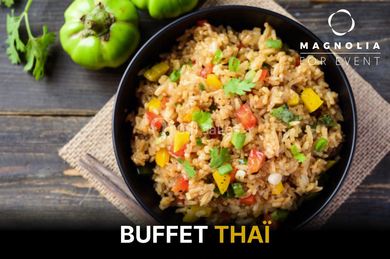 Assiette de riz sauté aux légumes colorés, garnie de coriandre, posée sur une table en bois avec des légumes en arrière-plan.