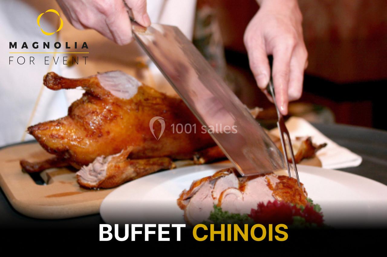 Une personne découpe un canard laqué sur une planche, prêt à être servi dans un buffet chinois.