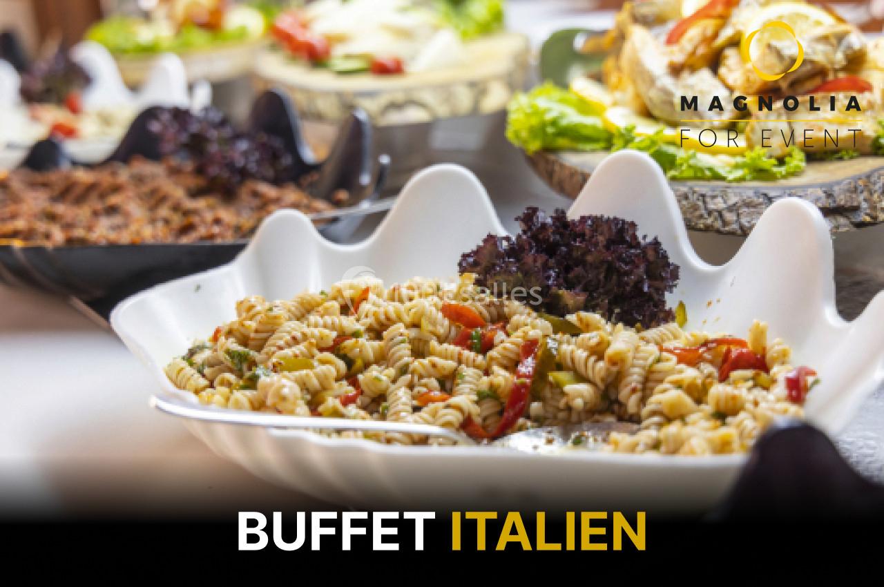 Assortiment de plats italiens avec des pâtes, légumes et salades présentés sur un buffet élégant.