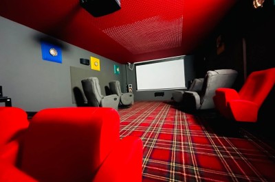 Piscine à débordement entourée de transats colorés sur une terrasse en bois, avec vue sur une campagne vallonnée.