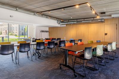 Canapé jaune moutarde capitonné avec coussins noirs, tables basses noires et cadres décoratifs accrochés au mur sombre.