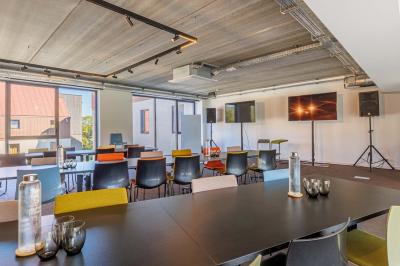 Canapé jaune moutarde capitonné avec coussins noirs, tables basses noires et cadres décoratifs accrochés au mur sombre.