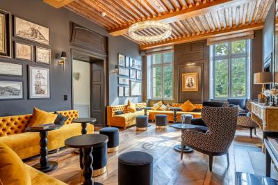 Canapé jaune moutarde capitonné avec coussins noirs, tables basses noires et cadres décoratifs accrochés au mur sombre.