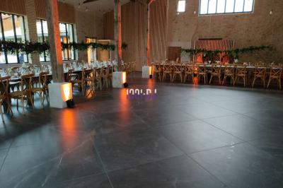 Vue d'une salle de réception avec des tables alignées, un bar en bois et un éclairage chaleureux sous une arche.