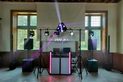 Vue d'une salle de réception avec des tables alignées, un bar en bois et un éclairage chaleureux sous une arche.