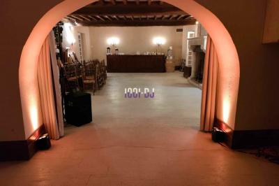 Vue d'une salle de réception avec des tables alignées, un bar en bois et un éclairage chaleureux sous une arche.