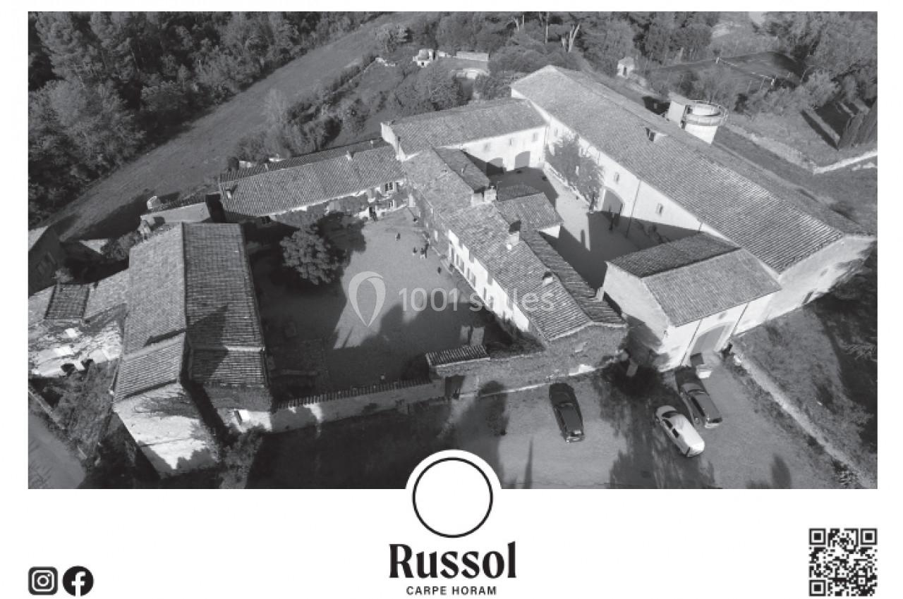 Vue aérienne en noir et blanc d'un domaine avec bâtiments anciens entourant une cour centrale, en milieu rural.