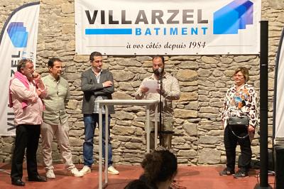 Des personnes assises dans une salle assistent à une présentation projetée sur un mur, avec documents en main.