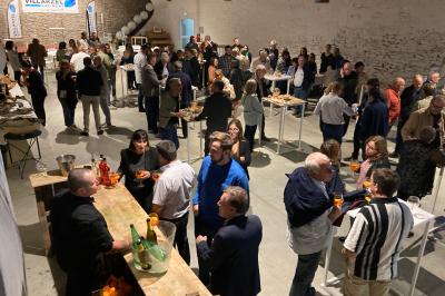 Des personnes assises dans une salle assistent à une présentation projetée sur un mur, avec documents en main.