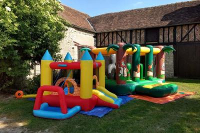Deux structures gonflables colorées installées sur une pelouse, près de bâtiments en pierre et en bois.