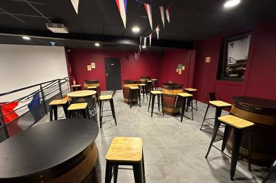 Un homme pose dans un magasin de boissons, tenant deux bouteilles devant un présentoir de bières variées.