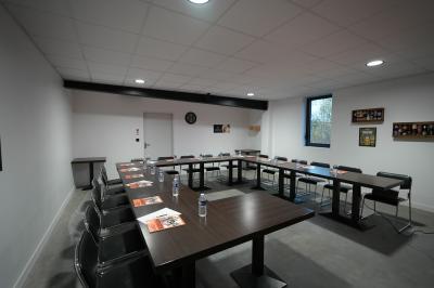 Un homme pose dans un magasin de boissons, tenant deux bouteilles devant un présentoir de bières variées.