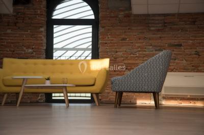 Bâtiment en briques rouges avec une allée bordée de pelouses et des drapeaux visibles au loin sous un ciel dégagé.