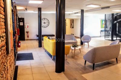 Bâtiment en briques rouges avec une allée bordée de pelouses et des drapeaux visibles au loin sous un ciel dégagé.