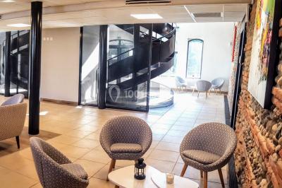 Bâtiment en briques rouges avec une allée bordée de pelouses et des drapeaux visibles au loin sous un ciel dégagé.