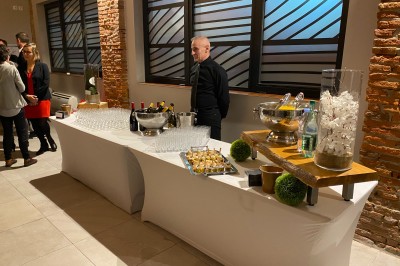 Bâtiment en briques rouges avec une allée bordée de pelouses et des drapeaux visibles au loin sous un ciel dégagé.