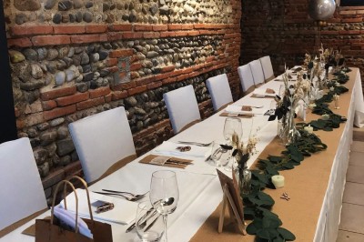 Salle lumineuse avec murs en briques, tables hautes, fauteuil jaune et décorations minimalistes.