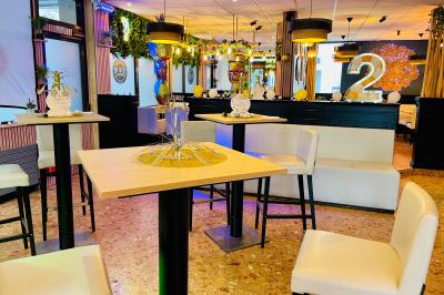 Salle de bar avec tables hautes, chaises, éclairage coloré et jeux de lumière dans une ambiance nocturne.